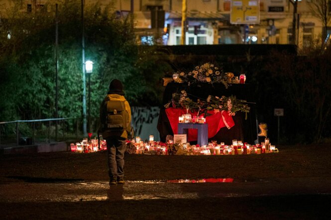 Eine Person steht vor dem „Blauen Klavier“ im Park Schöntal, um das Kerzen und Blumen gelegt wurden, die an den tödlichen Messerangriff erinnern