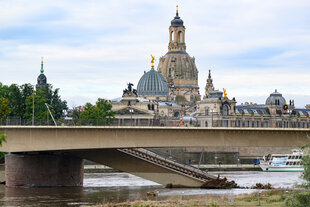 Das Bild zeigt eine Dresdner Ansicht mit Frauenkirche und eingestürzter Carolabrücke.