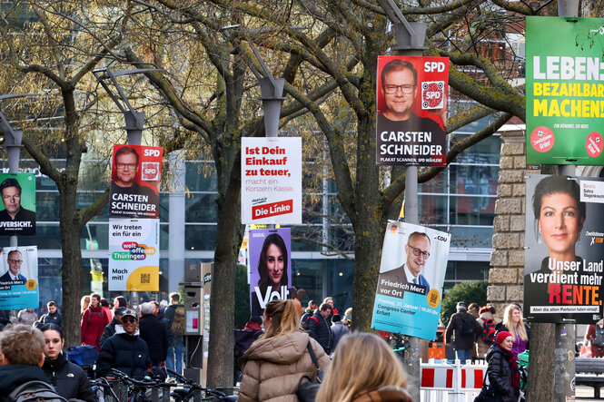 Das Bild zeigt eine Demonstration gegen Rechts, im Hintergrund sind die aktuellen Wahlplakate der Bundestagswahl 2025 zu erkennen.