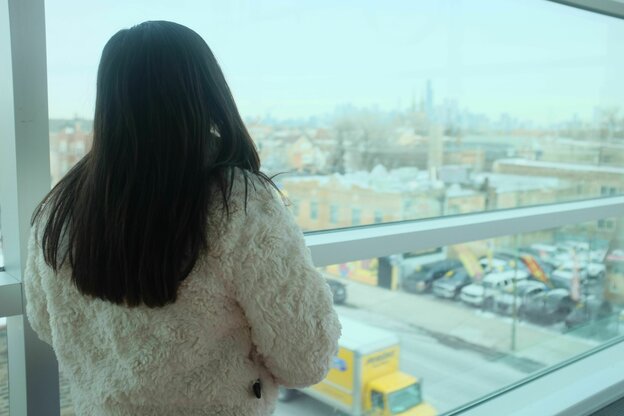 Eine Frau von hinten schaut aus dem Fenster