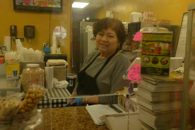 Eine Frau steht lächelnd hinter der Theke eines Cafés