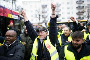 BVG-Streikende in geleben Warnwesten, im Hintergrund ein Bus der BVG