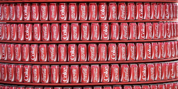Coca-Cola-Dosen stehen in einem Regal.