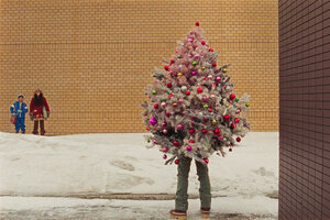 Ein geschmückter Tannenbaum mit Beinen steht vor einer beigen Wand