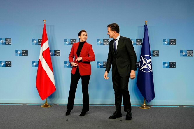 Mette Frederiksen und Mark Rutte stehen vor den Fahnen Dänemarks und der Naot