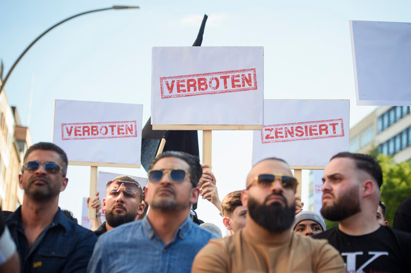 junger Männer mit Bärten und Sonnenbrillen halten Schilder, auf denen steht "verboten" und "zensiert"