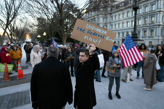 Protestierende gegen das Einfrieren der Leistungen mit Schildern und USA-Flaggen