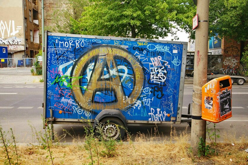 Ein Auto-Anhänger voller Graffiti und mit einem großen "A" im Kreis - dem Zeichen der Anarchisten steht auf der Straße