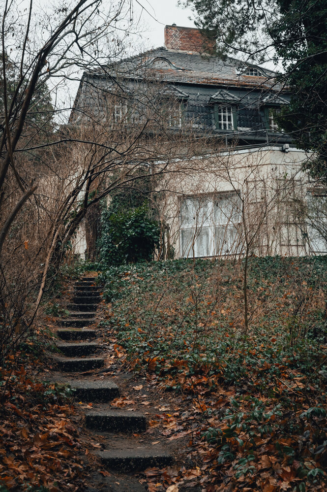 Stufen gehen zu einer Villa hinauf durch einen Garten