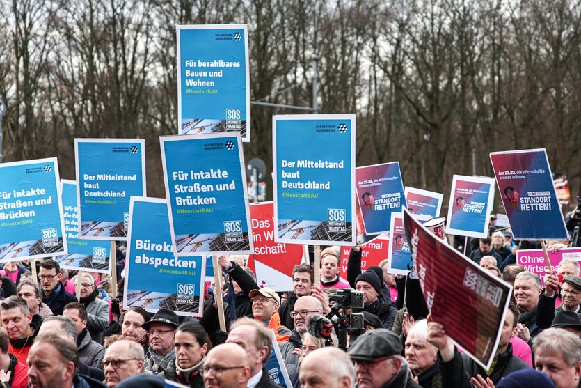 Menschen auf Demonstration mit vorgedruckten Schildern, z.B. "Bürokratie abspecken"