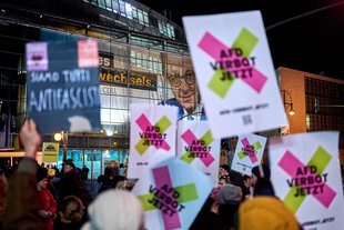 Plakat "AfD Verbot Jetzt", "Siamo tutti Antifacisti" - Protestaktion vor dem Konrad-Adenauerhaus in Berlin, an dessen Fassade ein großes Porträt von Friedrich Merz prangt