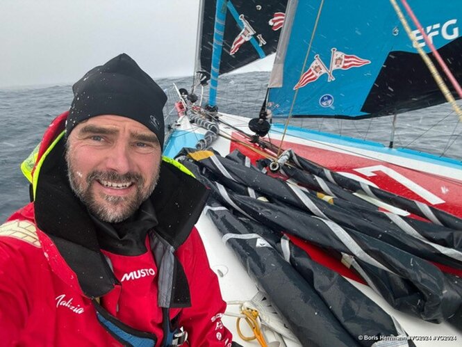 Boris Herrmann mit Jacke und Mütze fotografiert sich auf seinem Segelboot