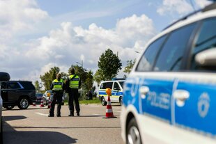 Polizisten stehen auf der Strasse, viele Polizeiaustos stehen rum