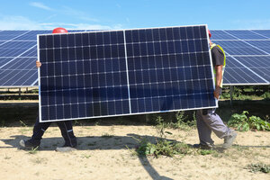 2 Menschen tragen ein Solarpaneel