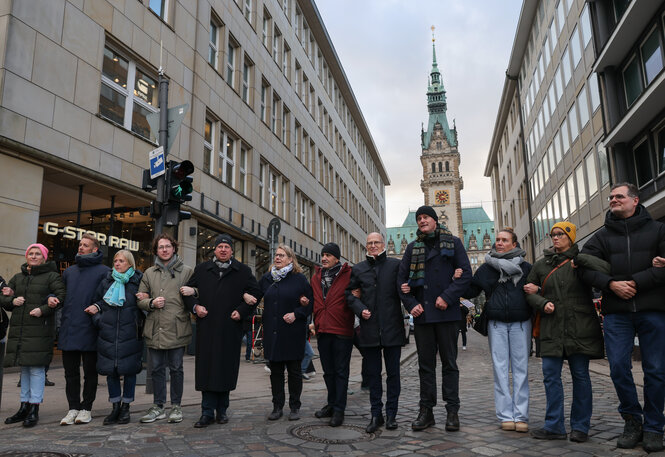 Bürgermeister Peter Tschentscher und FC St. Pauli-Präsident Oke Göttlich stehen mit anderen in einer Menschenkette vorm Hamburger Rathaus