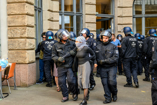 Polizist:innen und Aktivist:innen vor einem Gebäude.