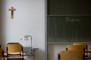 Ein Klassenzimmer mit einem Kreuz an der Wand.