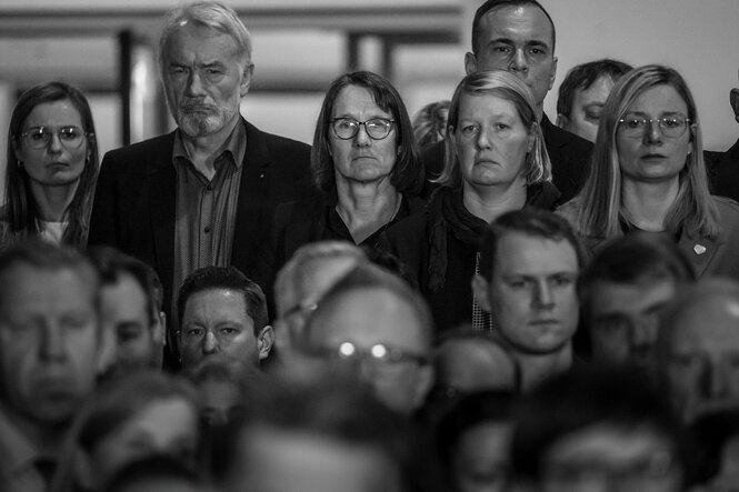 Menschen mit versteinerten Gesichtern stehen eng beieinander