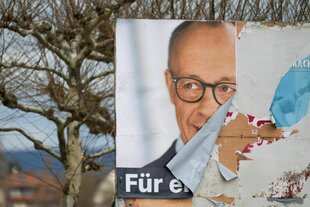 Ein abgerissenes Plakat mit Friedrich Merz als Bild.