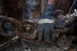 Ein Arbeiter fasst beim Schiffsrecycling eine rostige Kette