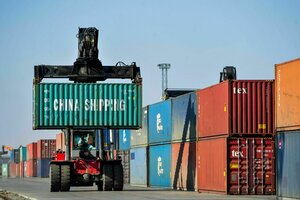 Ein Mann rangiert Container für die Weiterverladung in einer Logistikstation