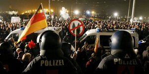 Polizisten in Kampfmontur, dahinter Demonstraten mit Deutschlandfahne