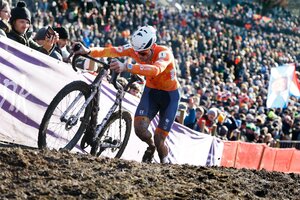 van der Poel schiebt sein Rennrad auf schlammigem steilen Untergrund, im Hintergrund Hunderte von Zuschauern