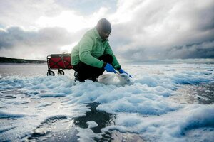 Ein Mann an einem Strand sammelt Schaumproben ein