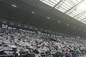 Fans halten schwarze Schilder in einem Fußballstadion hoch