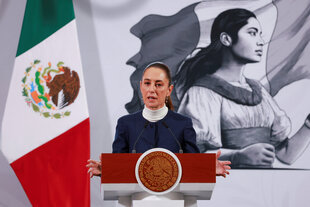 Mexikos Präsidentin Claudia Sheinbaum spricht am Montag neben der Nationalflagge und einem Mandgemälde zur Presse in Mexiko-Stadt.