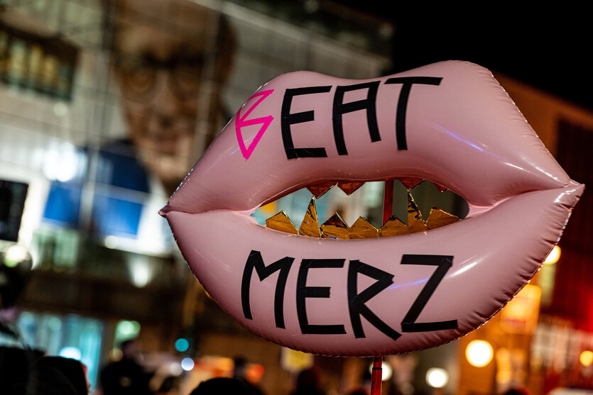 Ein Luftballon in Kuss-Form mit der Aufschrift "Beat Merz" bei einer Demonstration