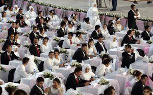 Zahlreiche Bräute und Bräutigame sitzen an Tischen