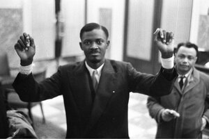 Schwarz-weiß-Foto von Patrice Lumumba, der beide Hände hochhält