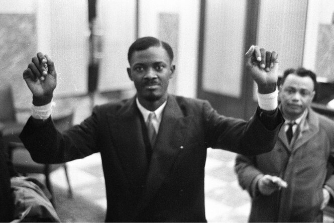 Schwarz-weiß-Foto von Patrice Lumumba, der beide Hände hochhält