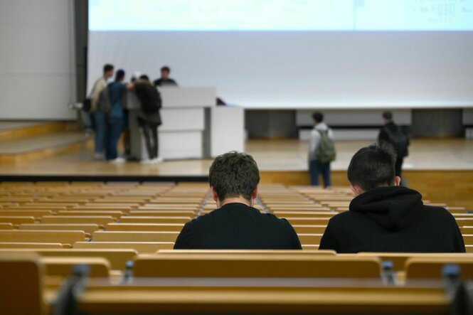 Zwei Menschen sitzen in einem Hörsaal