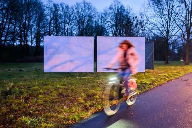 Leere Plakatwände, davor eine Person auf dem Fahrrad.