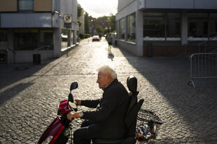 Eine alter Mensch fährt auf einem elektrischen Rollator