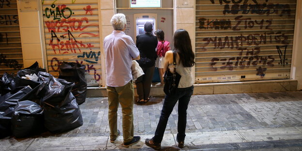 Menschen stehen Schlange vor einem Bankautomaten in Athen