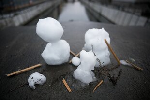 Zwei kleine halb geschmolzene Schneemänner stehen auf dem Gelände der Neuen Gertraudenbrücke im Bezirk Mitte.