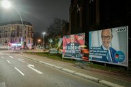 Eine leere Straße in der Nacht, rechts stehen Wahlplakatwände der Kanzlerkandidaten