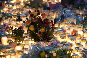 Eine Meer brennender Kerzen, in der Mitte ein Rosenstrauß