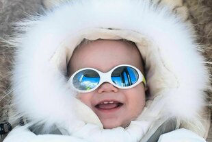 Kleines Baby trägt Schneeanzug im warmen Kinderwagen