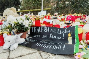 Zahlreiche Blumen, Kuscheltiere und Kerzen liegen am Tator in einem Park in Aschaffenburg. Dazwischen ein Plakat, auf dem steht: 