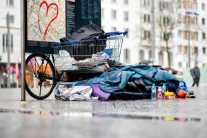 Die Habseligkeiten eines Obdachlosen liegen auf dem Vorplatz des Bremer Hauptbahnhof. Zu sehen sind ein Einkaufswagen mit Kleidung, daneben Schlafsack, etwas zu essen und zu trinken.