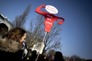 Auf einer Demo hält eine Frau ein Schild in Form eines Uterus hoch. Darauf steht 