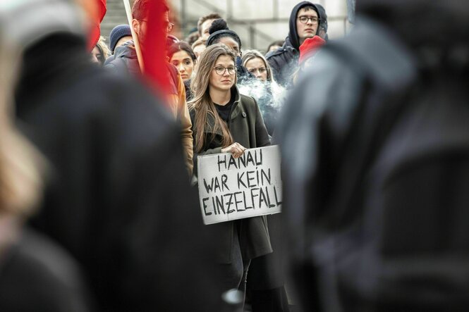 Bei einer Gedenkdemo in München am 19. Februar 2023 gedenken Menschen den Opfern des rassistischen Anschlags in Hanau. Ein Frau trägt ein Schild mit der Aufschrift "Hanau war kein Einzelfall"