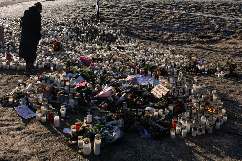 Eine Person steht vor den Blumen und Kerzen, die für die ermordeten Menschen an der Schule in Örebro abgelegt wurden