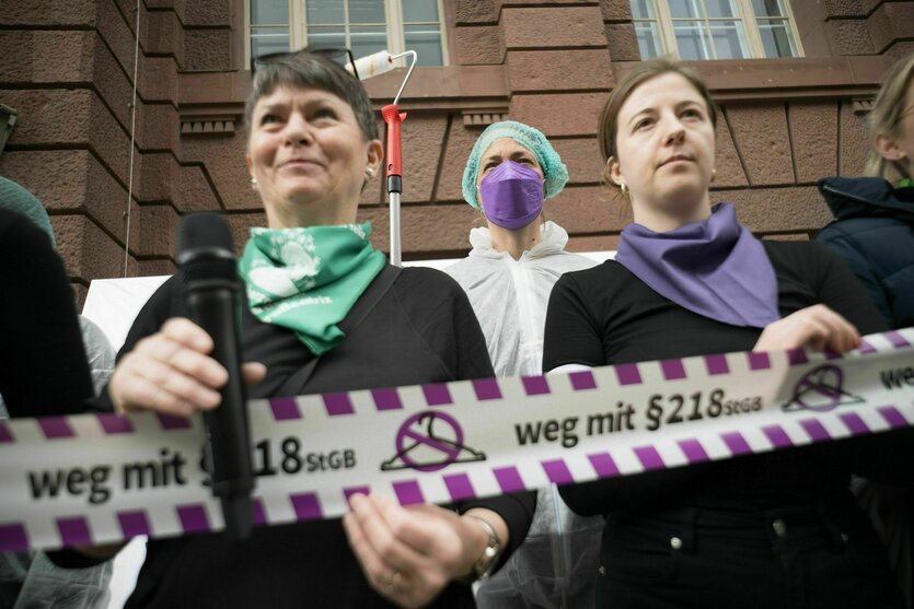 Einige Frauen stehen nebeneinander und halten ein Band mit der Aufschrift „Weg mit dem §218 StGB“.