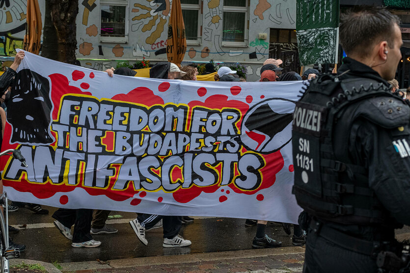 Eine Menschengruppe hinter einem Transparent mit der Aufschrift "Freedom for the Budapest Antifascists"