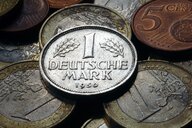 Eine alte D-Mark-Münze liegt auf Euro- und Cent-Münzen